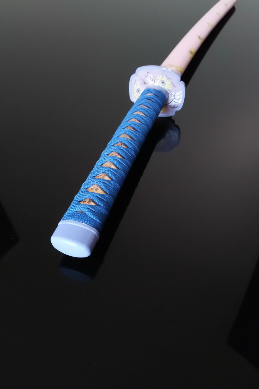 Dettaglio del pomolo (kashira) bianco-lilla della katana Kokushibou Demon Slayer con avvolgimento tsuka in cordone blu intrecciato e tsuba bianca decorata – replica da collezione di Tsugikuni Michikatsu per cosplay Kimetsu no Yaiba – sfondo scuro con piano a specchio