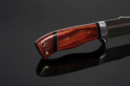 Detalle del mango de madera natural marrón rojizo del cuchillo de hoja fija con remaches dorados y guarda de metal – fondo oscuro con efecto espejo