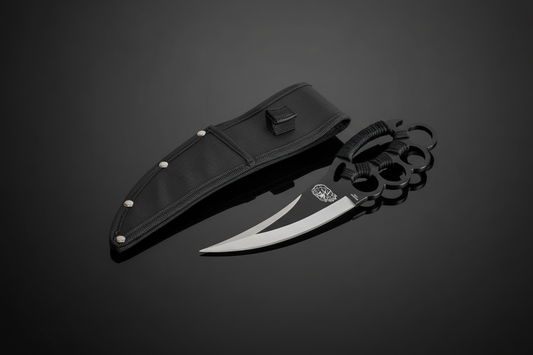 Coltello tattico Black Mamba Knuckle Duster con guardia a 4 anelli in acciaio nero e lama curva bitonale accanto al fodero in Cordura nera – sfondo scuro con piano a specchio